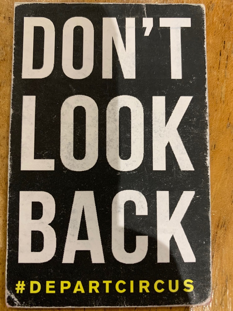 A photograph of a card distributed to audiences at the Depart shows. The paper is slightly worn. Yellow writing in block letters on a black background state You are entering our place. Walk in silence. Follow the light. Don’t look back. #departcircus @2017Hull
